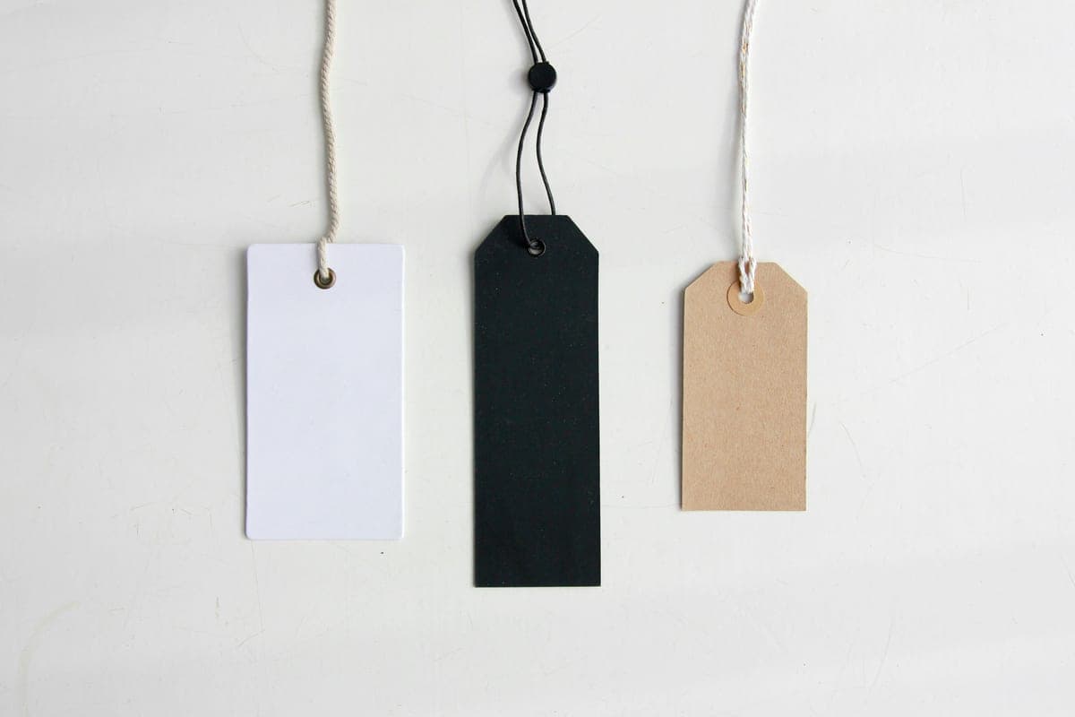 Price tags hanging on strings against a white wall